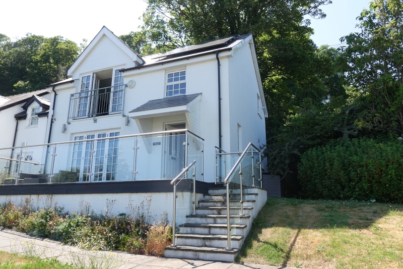 Unser Ferienhaus in Wales. Ein weißer Neubau mit 2 Etagen. Treppen führen zur Terasse. Bodentiefe Fenster oben und unten erlauben einen Blick auf das Meer.